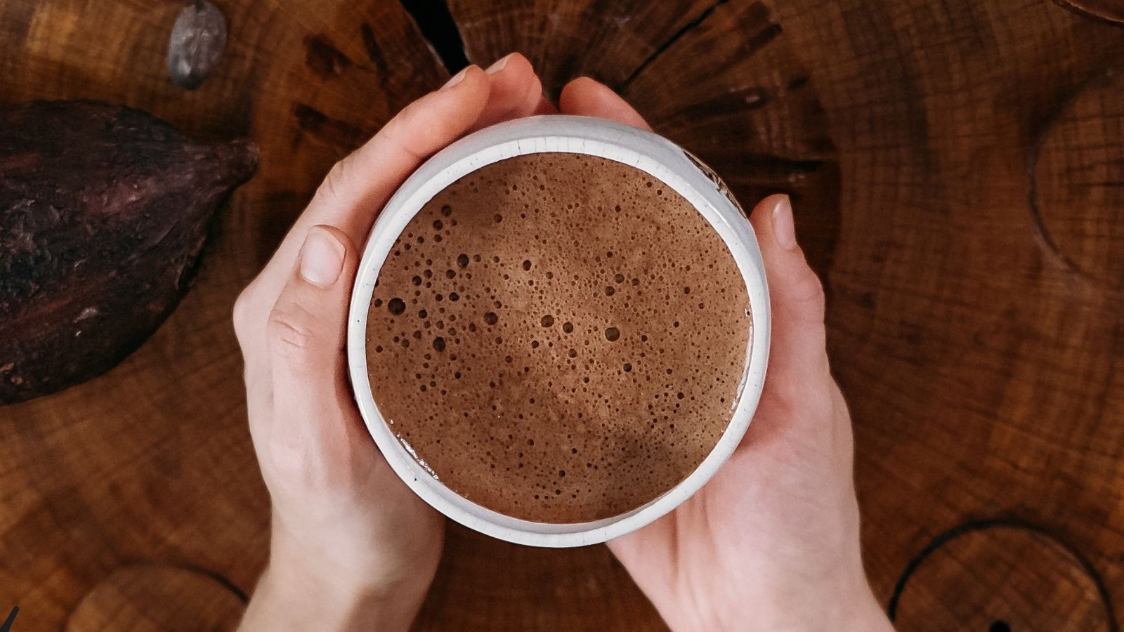 Handen rond een warme kop ceremoniële cacao